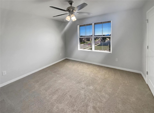 carpeted spare room featuring baseboards and ceiling fan