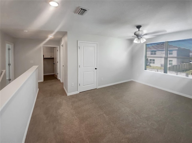 empty room featuring a ceiling fan, carpet, visible vents, and baseboards