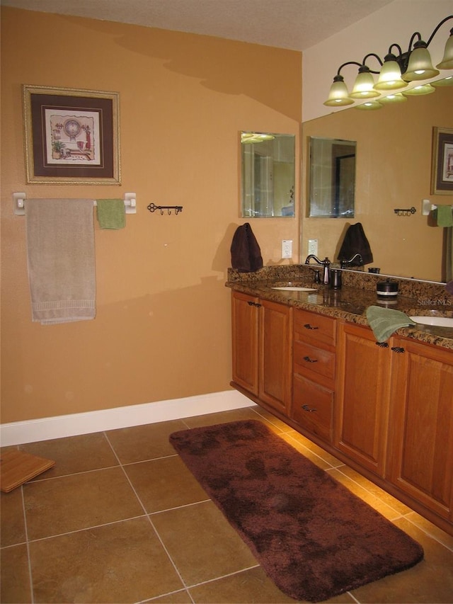 bathroom with tile patterned floors, double vanity, baseboards, and a sink