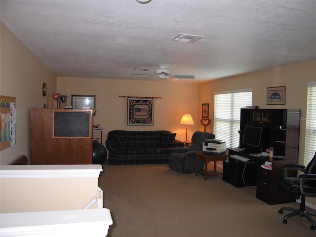 carpeted living area with visible vents, a textured ceiling, and a ceiling fan