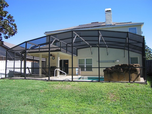 back of house with fence, a yard, stucco siding, a lanai, and a patio area