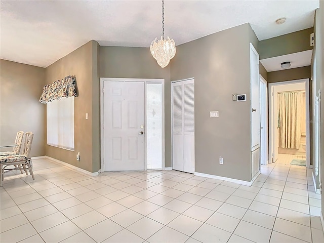 entrance foyer featuring light tile patterned floors, baseboards, and a notable chandelier