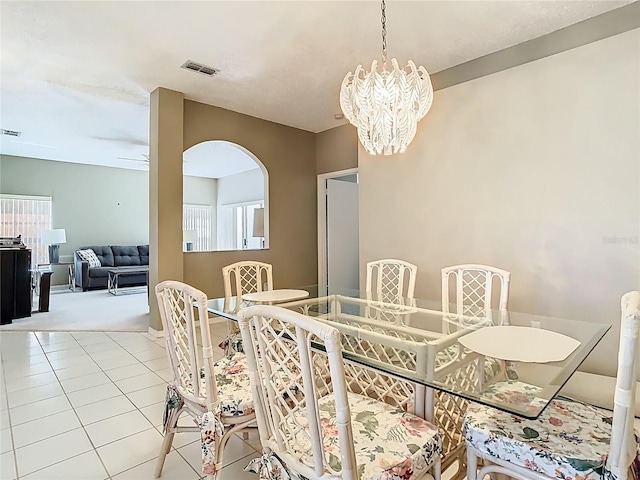 dining space with light tile patterned floors, ceiling fan with notable chandelier, and visible vents