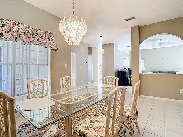 dining space with tile patterned floors, visible vents, ceiling fan with notable chandelier, and baseboards