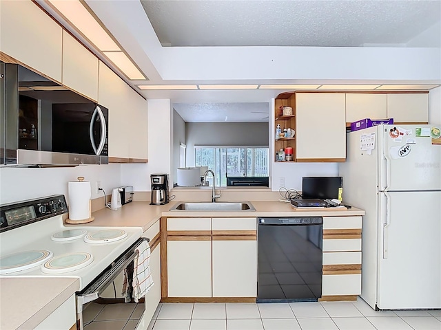 kitchen with a sink, a textured ceiling, white appliances, light countertops, and light tile patterned floors