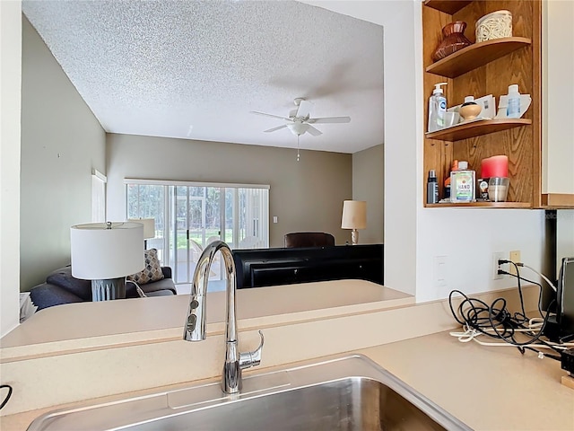 kitchen with open shelves, ceiling fan, a sink, a textured ceiling, and open floor plan