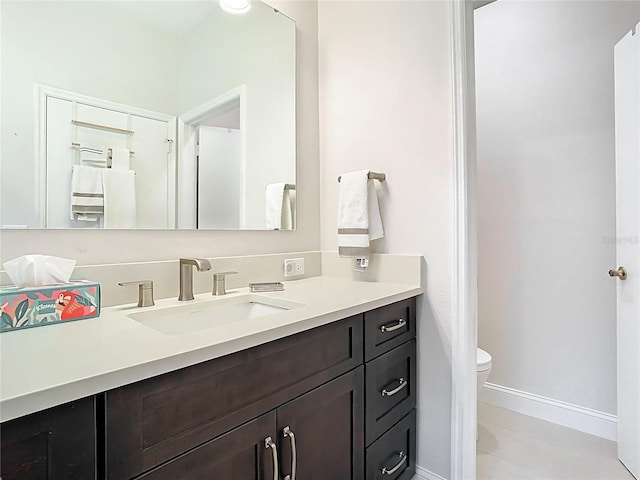 bathroom featuring tile patterned flooring, toilet, vanity, and baseboards