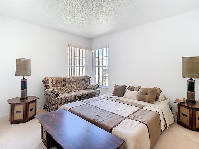 bedroom with light colored carpet and a textured ceiling