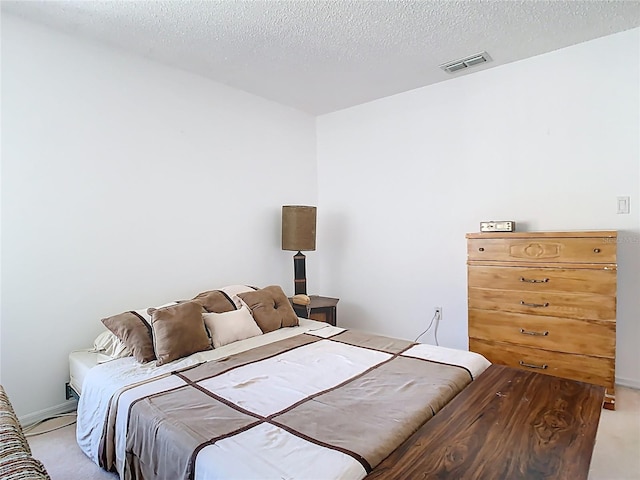 bedroom featuring a textured ceiling, baseboards, visible vents, and light carpet