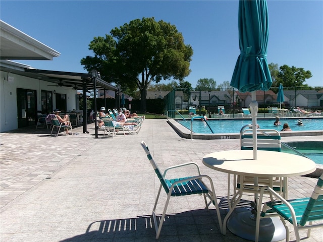 community pool with a patio, a ceiling fan, and fence