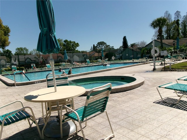 community pool with a patio area, a community hot tub, and fence