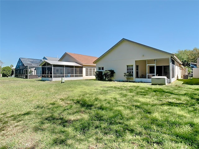 back of property with stucco siding, a lawn, and a sunroom