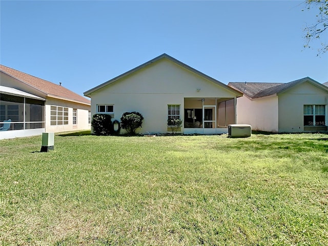 back of property featuring a lawn, a sunroom, and stucco siding