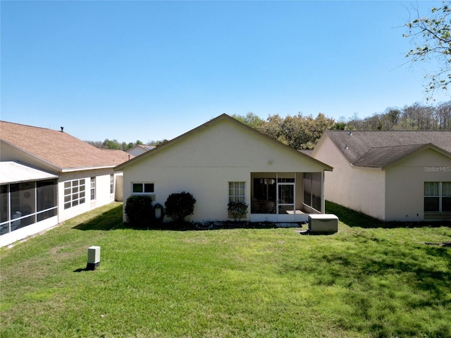 back of house featuring a yard, a sunroom, and stucco siding