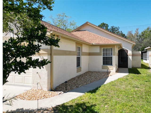 single story home featuring stucco siding, a front lawn, a garage, and roof with shingles