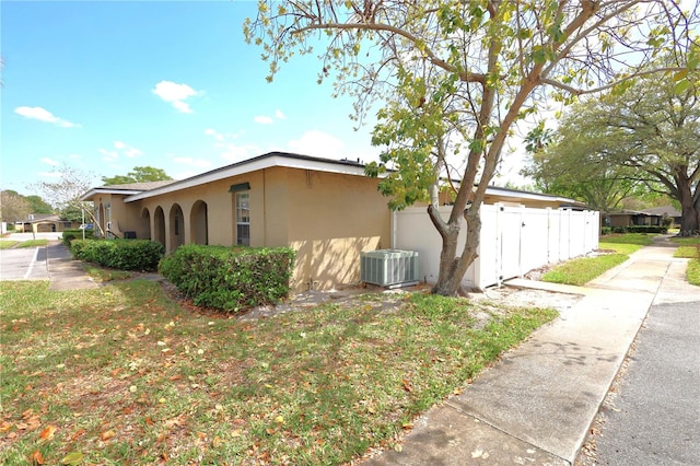 view of home's exterior featuring central air condition unit, fence, and stucco siding