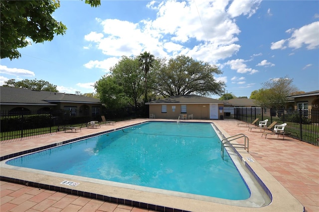 community pool with a patio area and fence