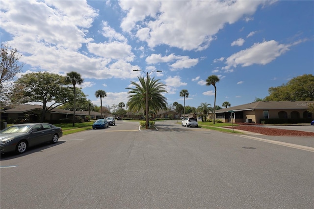 view of road with sidewalks, a residential view, curbs, and street lighting