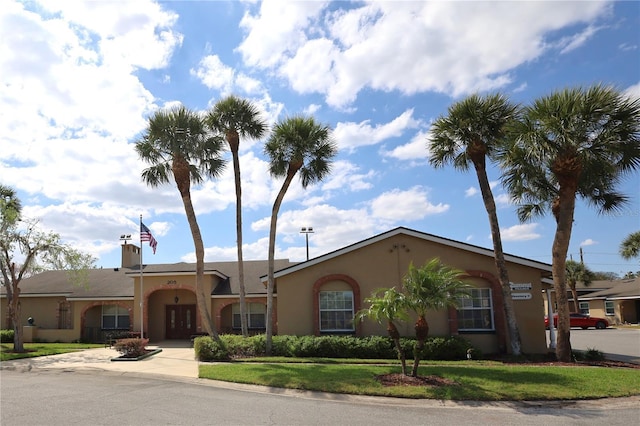 view of front facade with stucco siding, driveway, and a front lawn