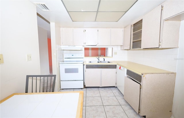 kitchen featuring white appliances, light tile patterned floors, visible vents, a sink, and under cabinet range hood