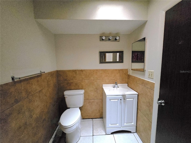 bathroom featuring vanity, a wainscoted wall, tile patterned floors, toilet, and tile walls