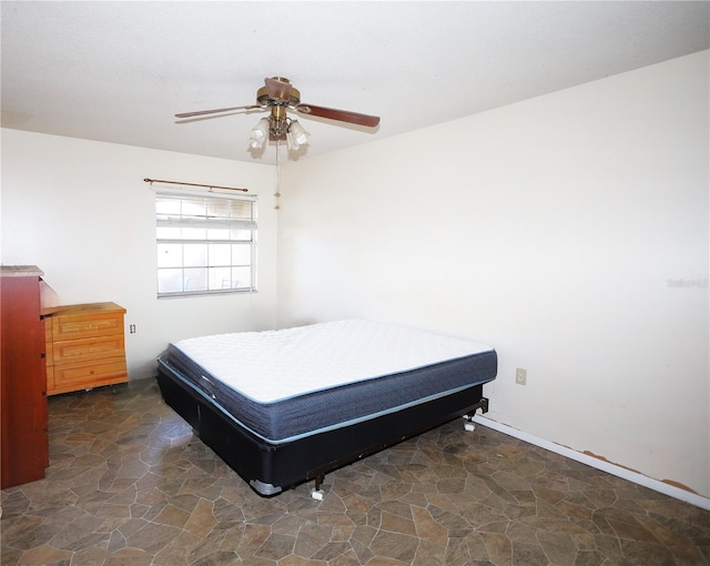 bedroom featuring ceiling fan and stone finish floor