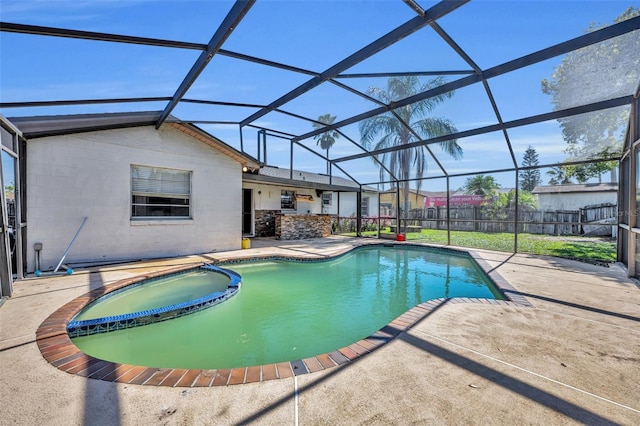 view of pool with glass enclosure, fence, a pool with connected hot tub, and a patio area