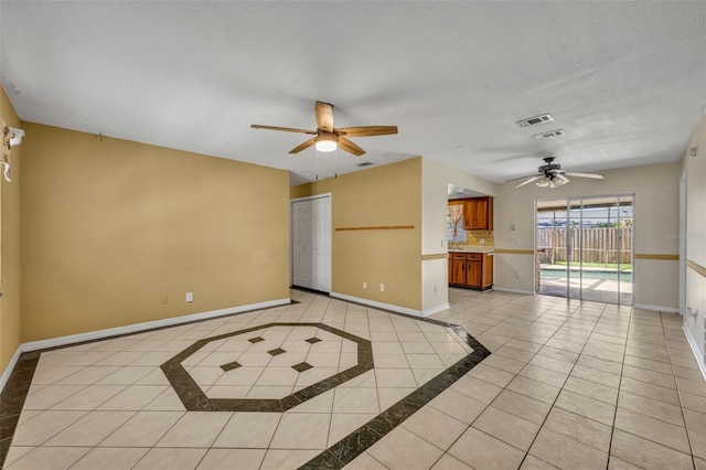 interior space featuring visible vents, light tile patterned flooring, a ceiling fan, and baseboards