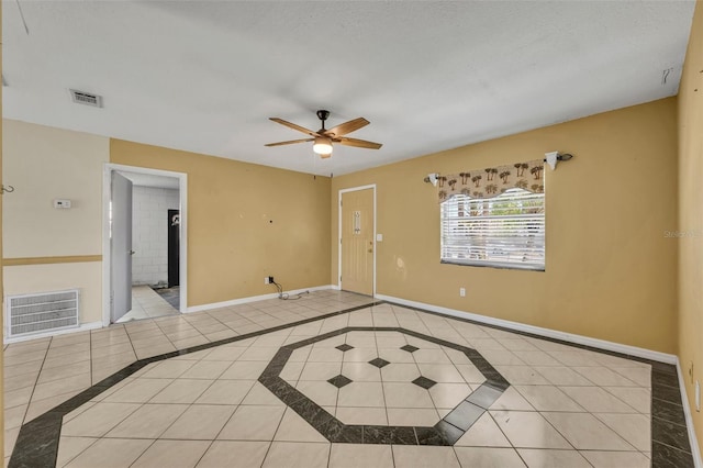 tiled empty room featuring a ceiling fan, visible vents, and baseboards