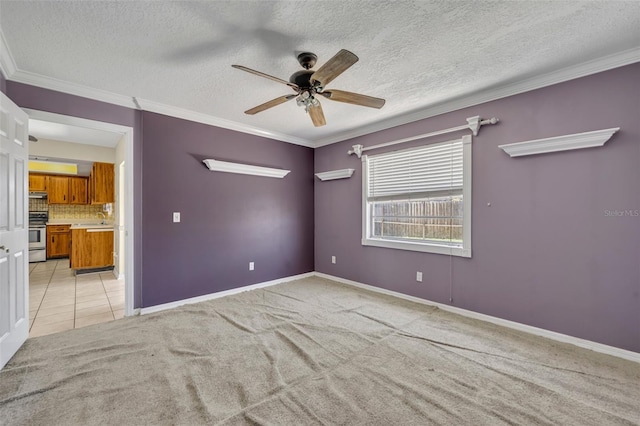 spare room with ceiling fan, ornamental molding, light carpet, light tile patterned floors, and a sink