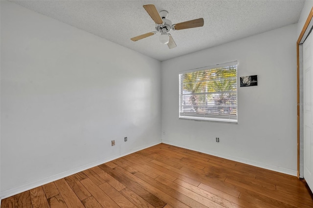 unfurnished room featuring baseboards, a textured ceiling, hardwood / wood-style floors, and a ceiling fan