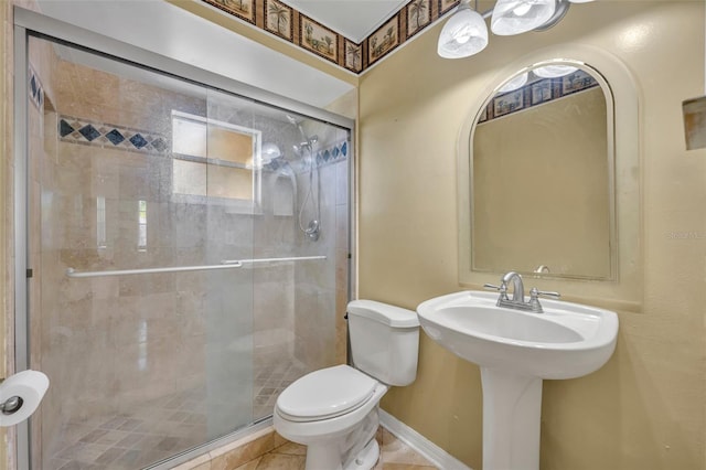 bathroom with toilet, baseboards, and a stall shower