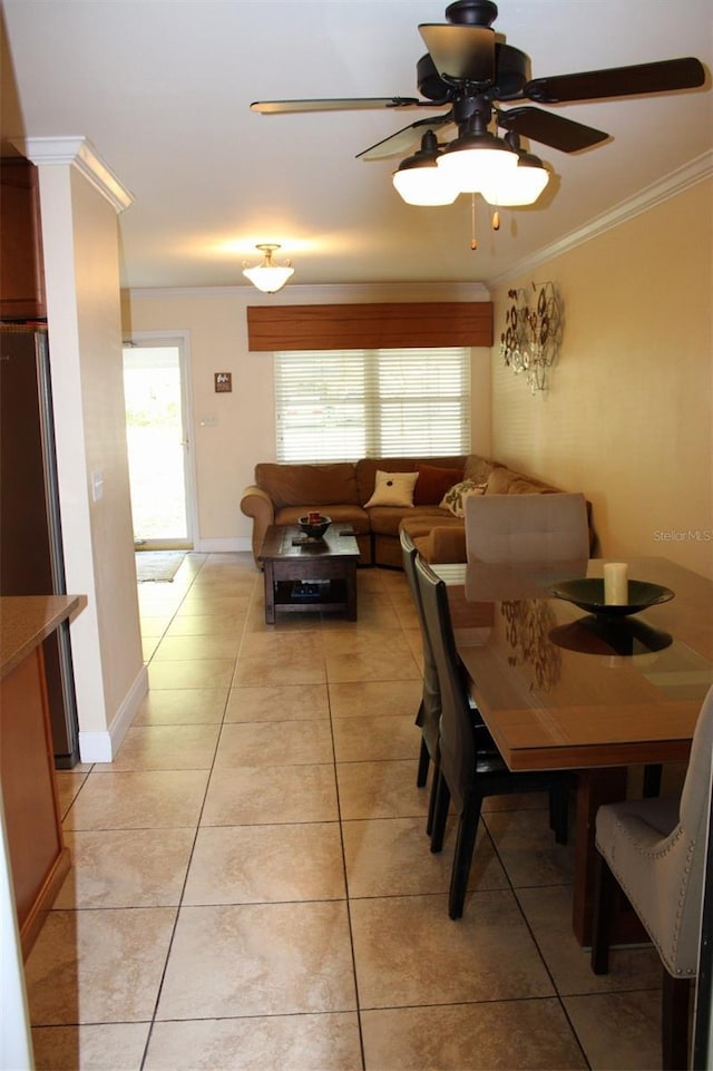 dining room featuring ceiling fan, light tile patterned floors, baseboards, and ornamental molding