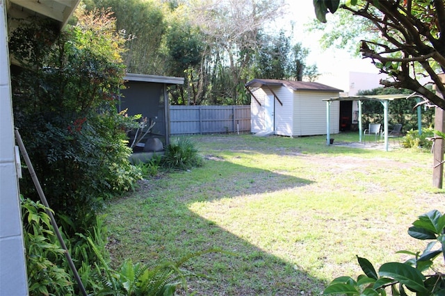 view of yard with an outbuilding, driveway, fence, a storage shed, and a sunroom