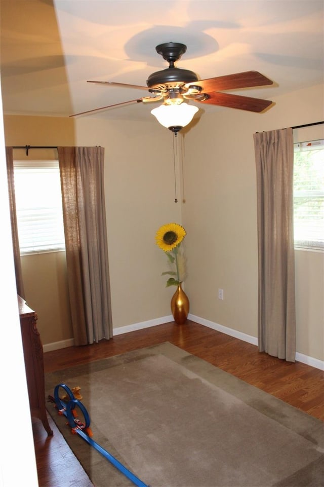 interior space featuring a ceiling fan, wood finished floors, and baseboards