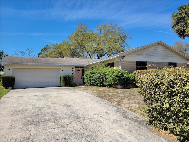 ranch-style home with brick siding, an attached garage, and driveway