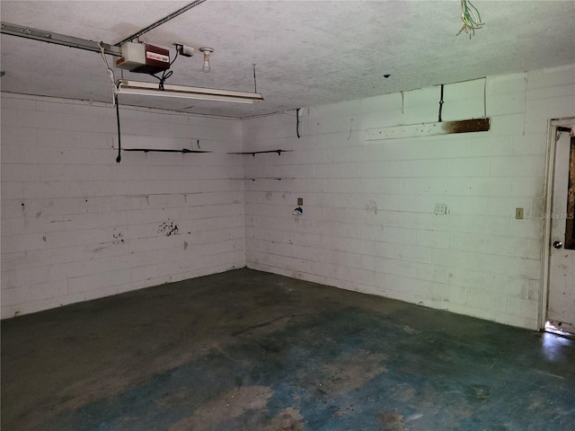 garage featuring concrete block wall and a garage door opener