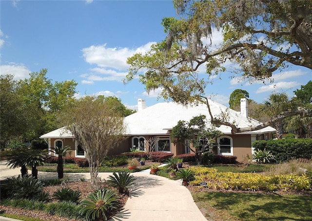 ranch-style house featuring stucco siding and a chimney