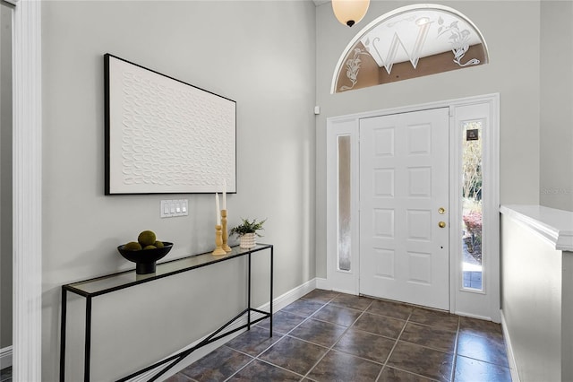 entryway with dark tile patterned floors, a healthy amount of sunlight, and baseboards