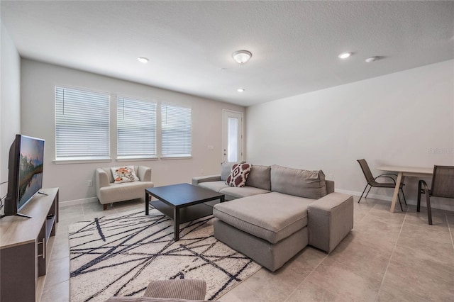 living area featuring light tile patterned floors, recessed lighting, a textured ceiling, and baseboards