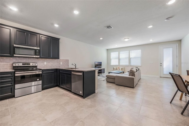 kitchen featuring light stone counters, visible vents, appliances with stainless steel finishes, and a sink