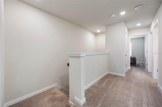 corridor featuring baseboards, an upstairs landing, and carpet flooring