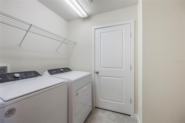 laundry area with laundry area, light tile patterned floors, and washing machine and dryer