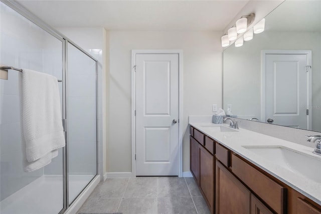 full bath featuring tile patterned floors, double vanity, a stall shower, and a sink