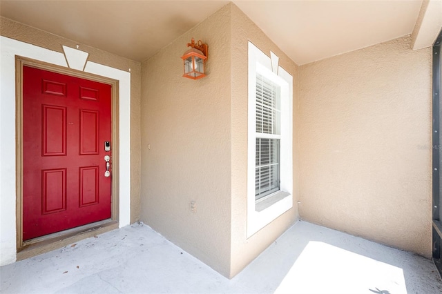 view of exterior entry featuring stucco siding and a porch