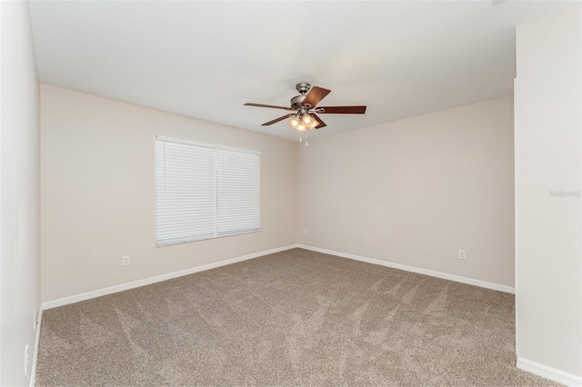 empty room with carpet flooring, a ceiling fan, and baseboards