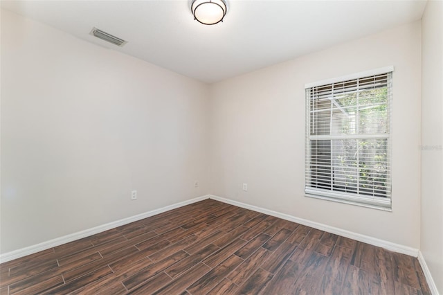 unfurnished room with visible vents, baseboards, and dark wood-style floors