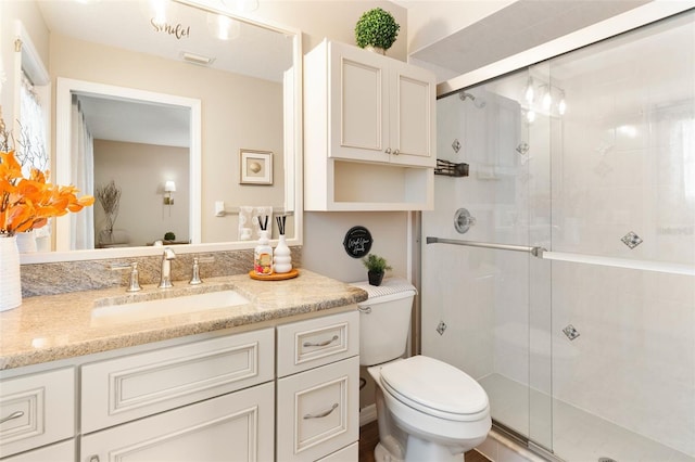 bathroom featuring vanity, toilet, visible vents, and a stall shower