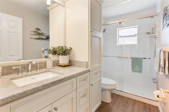 full bath featuring a shower stall, toilet, vanity, and wood finished floors