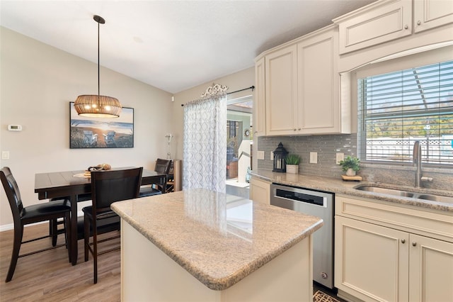 kitchen with tasteful backsplash, a kitchen island, dishwasher, vaulted ceiling, and a sink